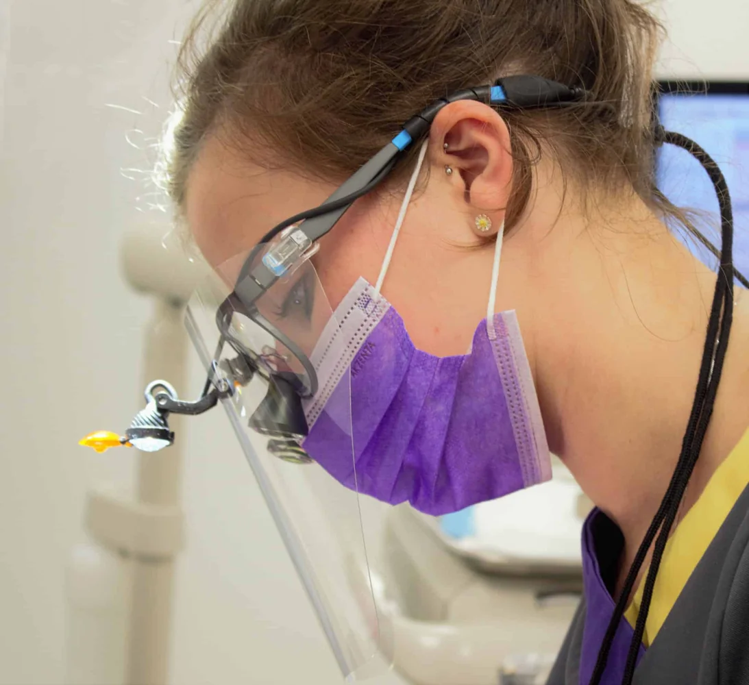 Smileworks dental therapist treating a patient using magnifying loupes.